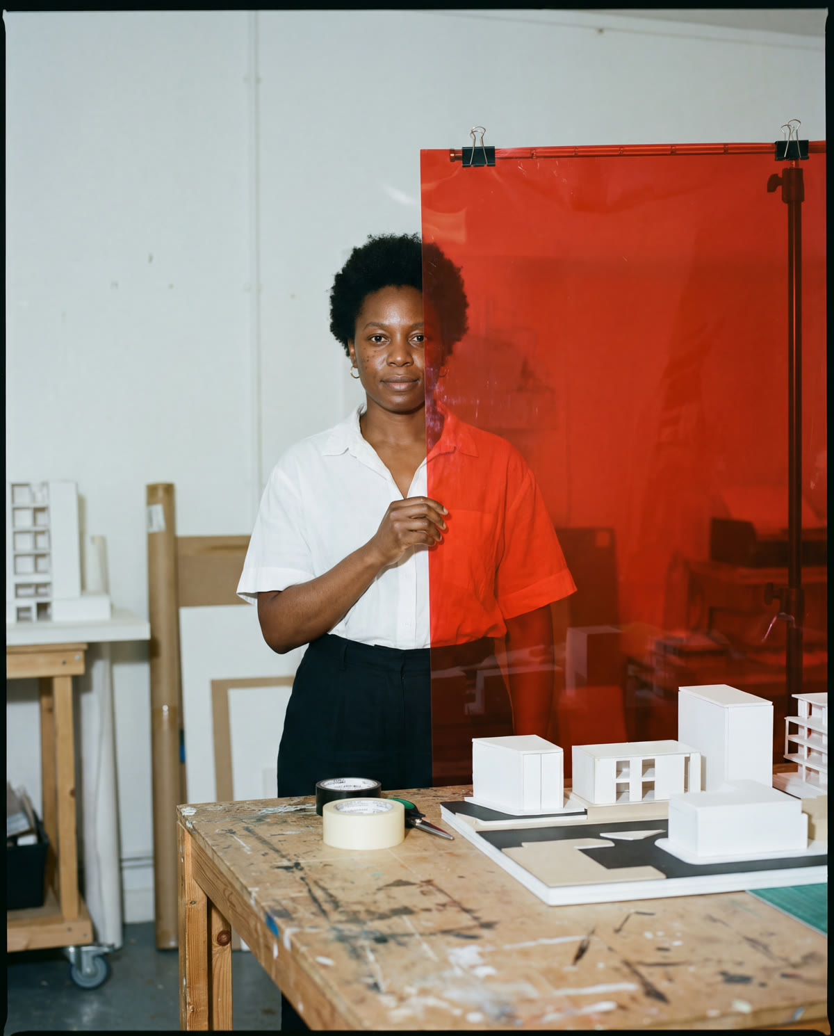 Set designer standing behind translucent red acetate in a daylight studio